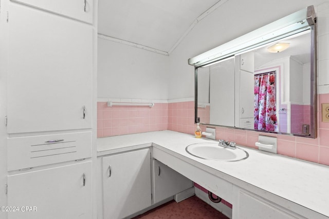 bathroom with lofted ceiling, tile walls, tasteful backsplash, and large vanity