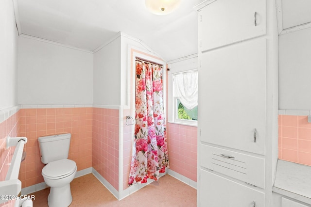 bathroom with toilet, tile floors, and tile walls