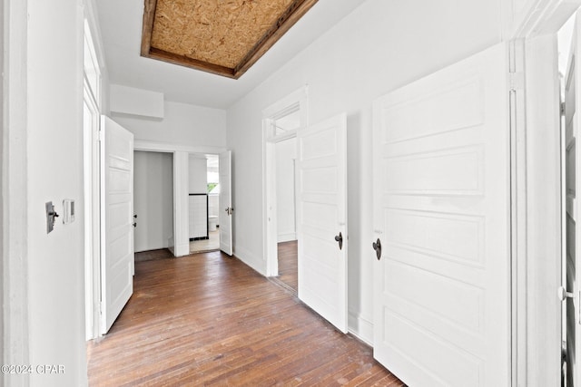 hallway with hardwood / wood-style floors and a tray ceiling