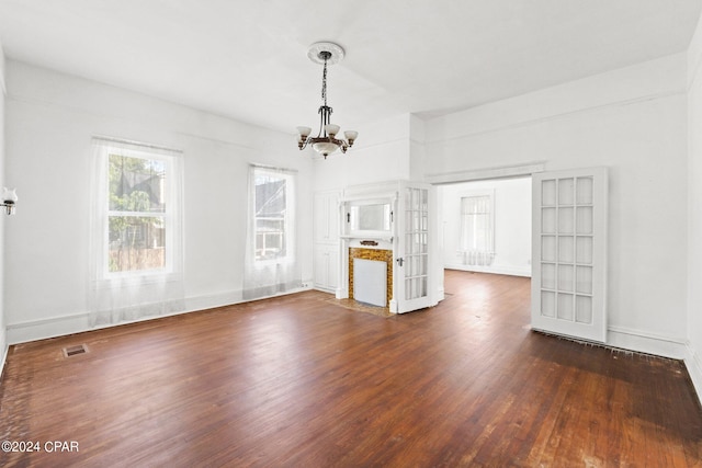 unfurnished living room featuring french doors, dark hardwood / wood-style flooring, and a chandelier