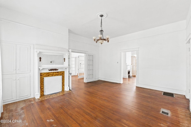 unfurnished living room featuring a notable chandelier and dark wood-type flooring