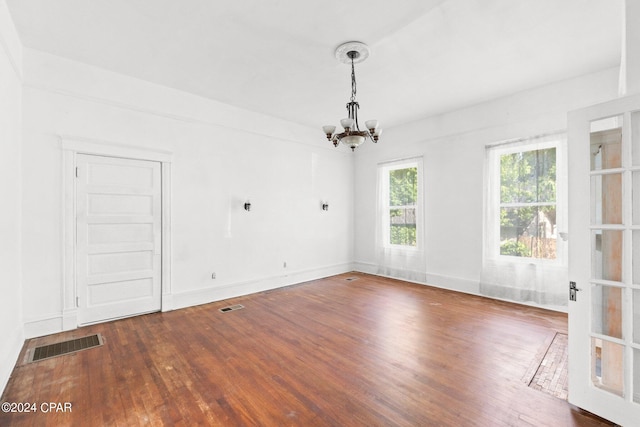 spare room with an inviting chandelier and dark hardwood / wood-style floors