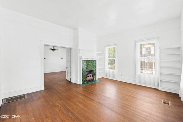 unfurnished living room featuring built in shelves and dark wood-type flooring