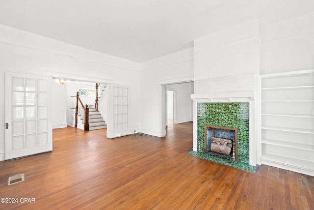 unfurnished living room featuring built in features and wood-type flooring