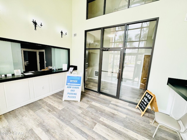 interior space with white cabinets, a high ceiling, and light wood-type flooring