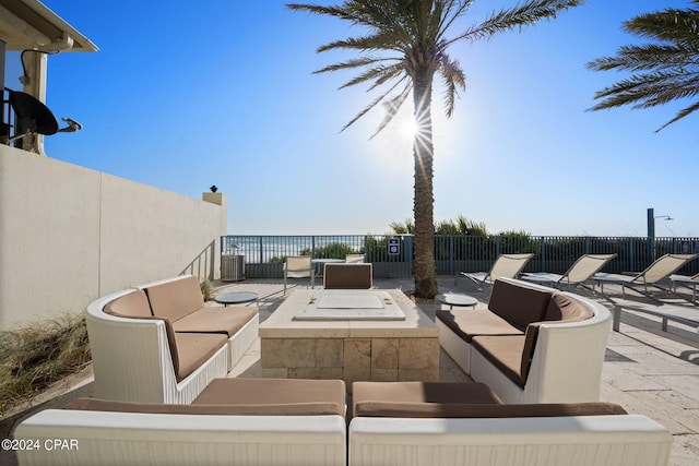 view of patio / terrace featuring central air condition unit and an outdoor living space with a fire pit