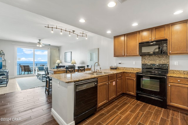 kitchen featuring dishwashing machine, light stone countertops, kitchen peninsula, sink, and ceiling fan