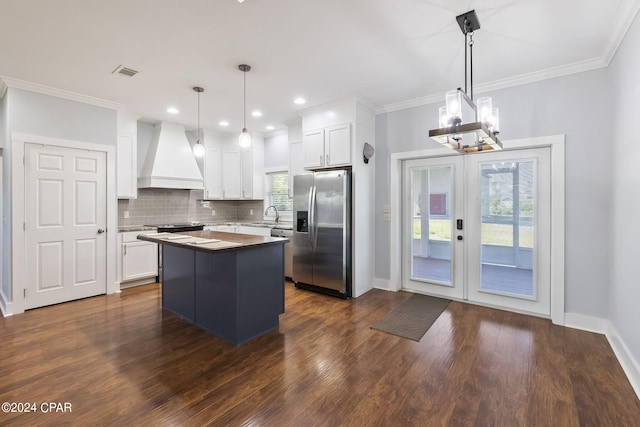 kitchen with hanging light fixtures, appliances with stainless steel finishes, custom range hood, and white cabinets