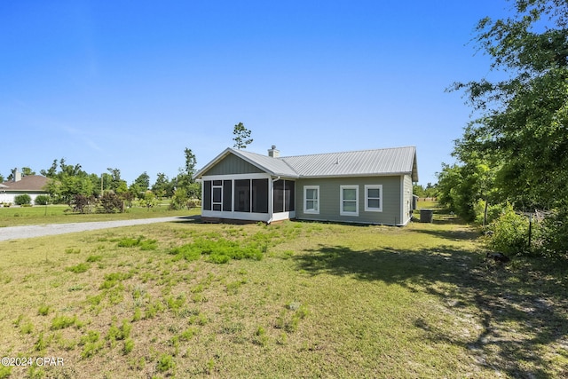 rear view of house with a sunroom and a lawn