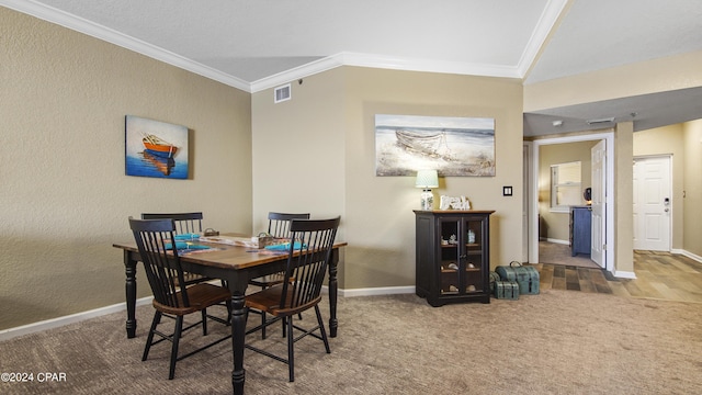 carpeted dining space featuring crown molding