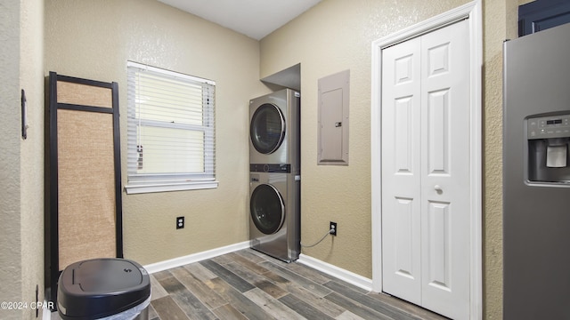 laundry area featuring electric panel, dark wood-type flooring, and stacked washer and clothes dryer