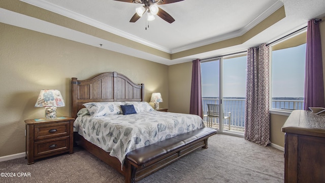 carpeted bedroom featuring a water view, ornamental molding, a tray ceiling, ceiling fan, and access to exterior