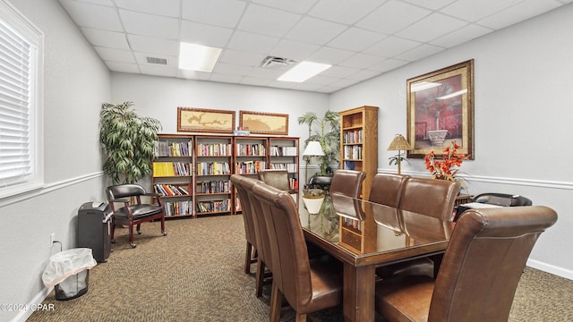 carpeted dining area featuring a paneled ceiling