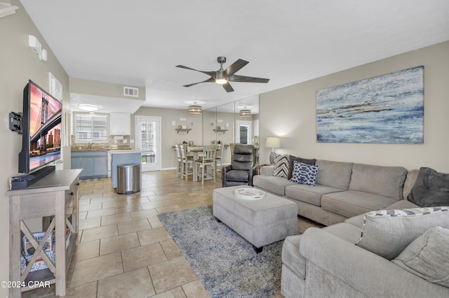 living room with sink, light tile patterned floors, and ceiling fan