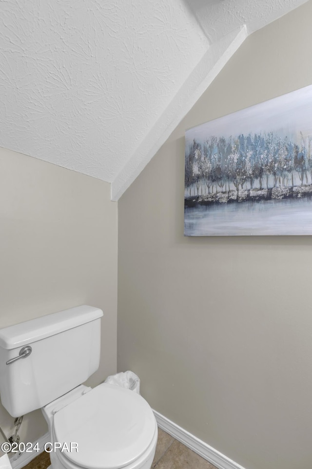 bathroom with lofted ceiling, toilet, and a textured ceiling