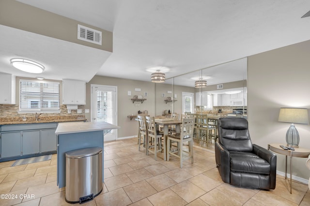 kitchen with blue cabinetry, tasteful backsplash, white cabinetry, sink, and light tile floors