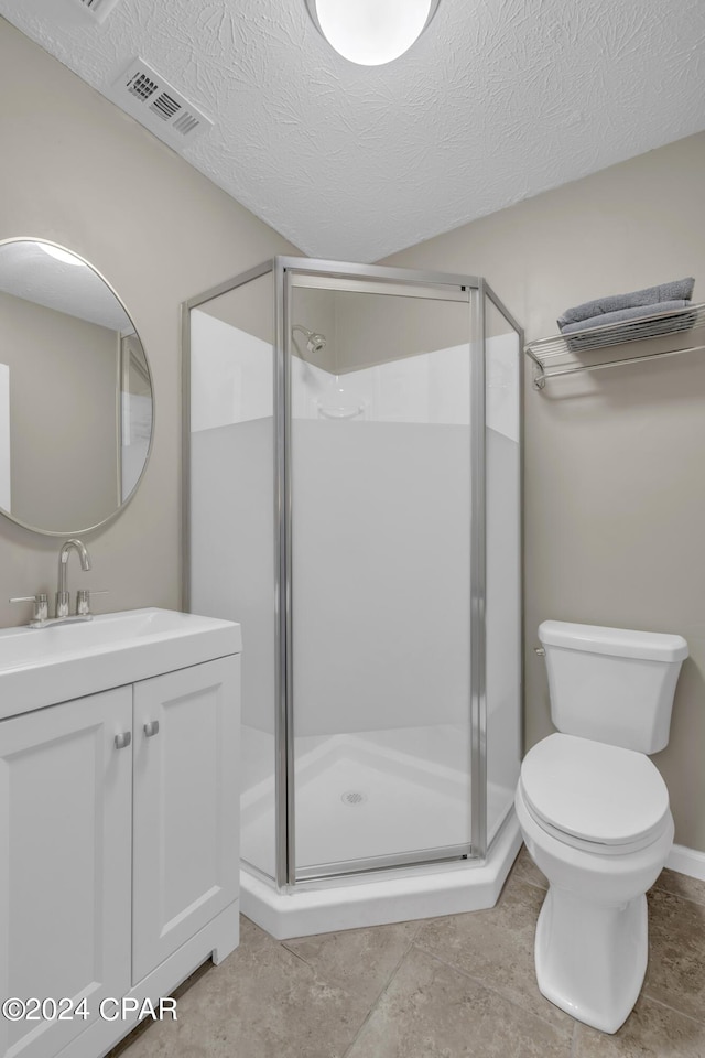 bathroom featuring toilet, vanity, a textured ceiling, and walk in shower