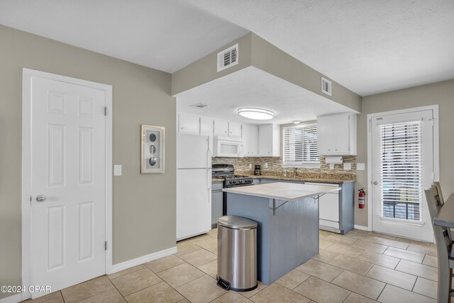 kitchen featuring backsplash, plenty of natural light, white appliances, and a breakfast bar area