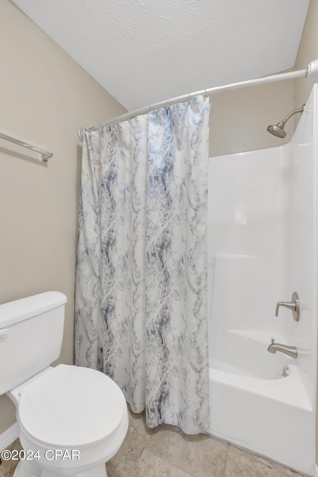 bathroom featuring tile patterned floors, shower / bath combination with curtain, a textured ceiling, and toilet