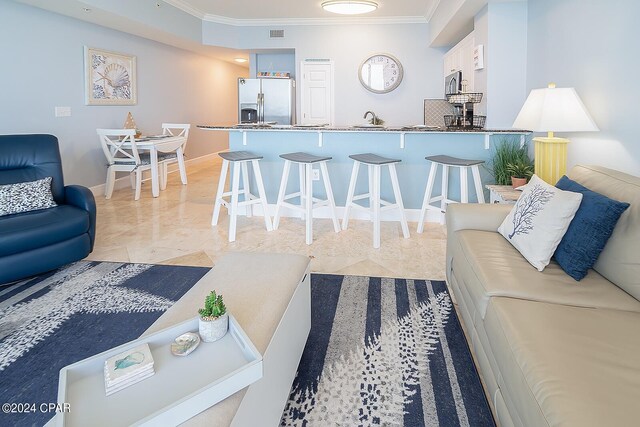 living room featuring ornamental molding, sink, and light tile floors