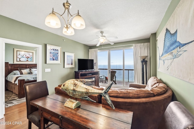 dining room featuring a water view, a textured ceiling, hardwood / wood-style floors, and ceiling fan