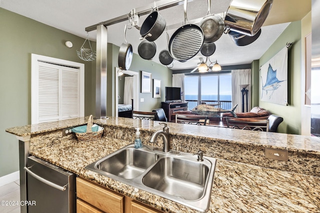 kitchen featuring a water view, light tile flooring, light stone counters, sink, and stainless steel dishwasher