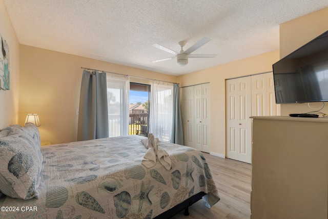 bedroom with two closets, ceiling fan, a textured ceiling, and light wood-type flooring