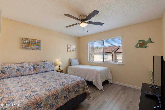 bedroom with ceiling fan, hardwood / wood-style flooring, and a textured ceiling