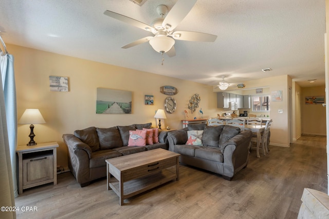 living room with hardwood / wood-style flooring, ceiling fan, and a textured ceiling