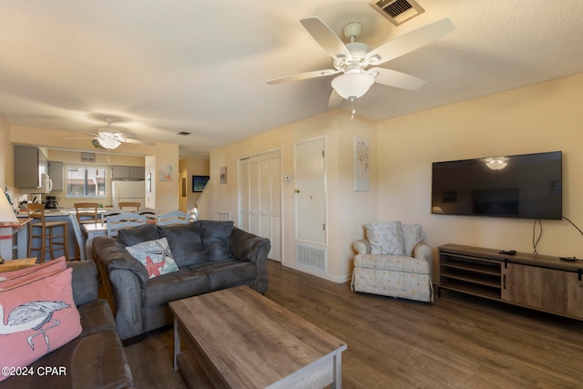 living room with ceiling fan, dark hardwood / wood-style floors, and a textured ceiling