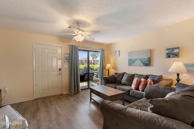 living room with dark hardwood / wood-style flooring, ceiling fan, and a textured ceiling