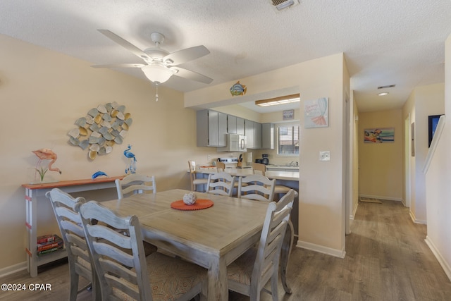 dining room featuring hardwood / wood-style floors, ceiling fan, and a textured ceiling