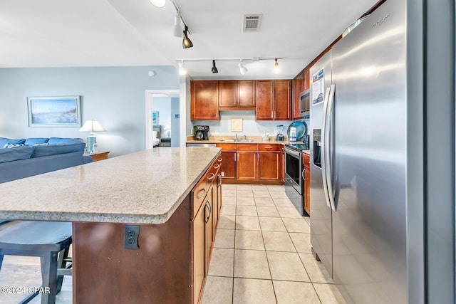 kitchen featuring light tile patterned floors, visible vents, a kitchen island, open floor plan, and stainless steel appliances