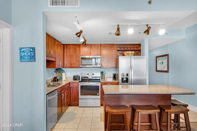 kitchen featuring appliances with stainless steel finishes, light tile patterned flooring, and track lighting