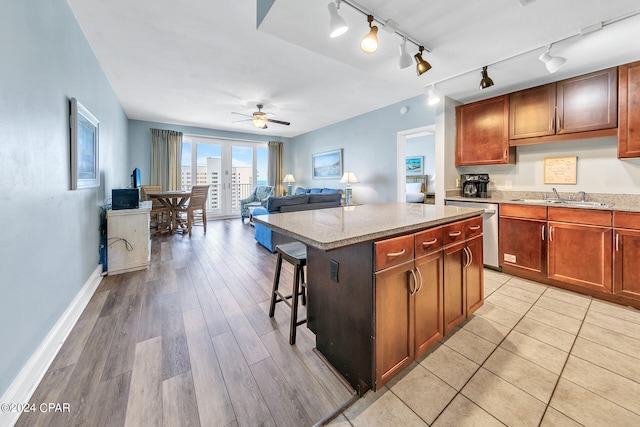 kitchen with ceiling fan, rail lighting, sink, a center island, and light hardwood / wood-style floors