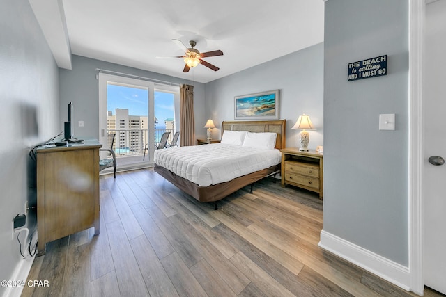 bedroom featuring a ceiling fan, access to outside, baseboards, and wood finished floors