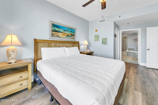 bedroom with visible vents, ensuite bathroom, ceiling fan, wood finished floors, and baseboards