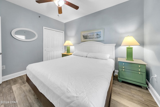 bedroom featuring a ceiling fan, a closet, baseboards, and wood finished floors