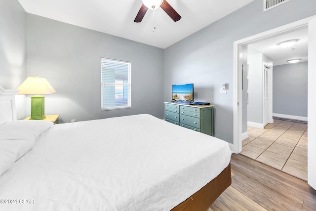 bedroom with visible vents, a ceiling fan, light wood-style flooring, and baseboards