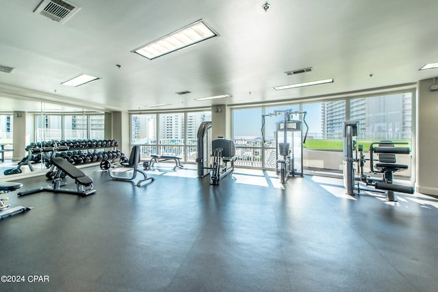 gym with a view of city, floor to ceiling windows, and visible vents