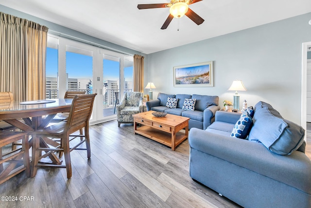 living room with a city view, ceiling fan, and wood finished floors