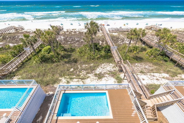 view of swimming pool with a water view and a view of the beach