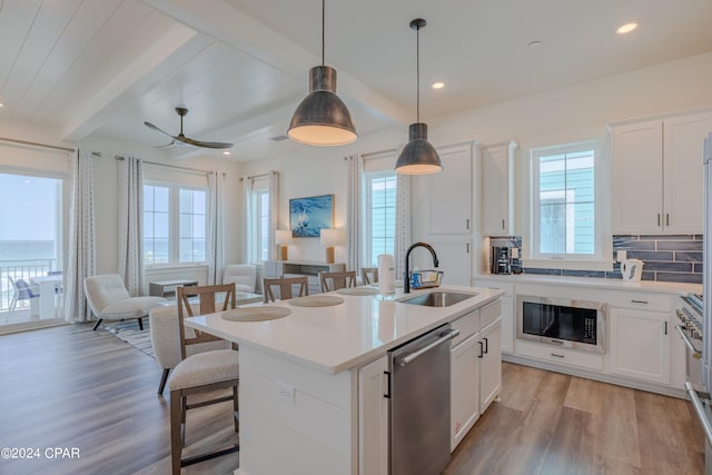 kitchen featuring light hardwood / wood-style flooring, a wealth of natural light, stainless steel appliances, and beam ceiling