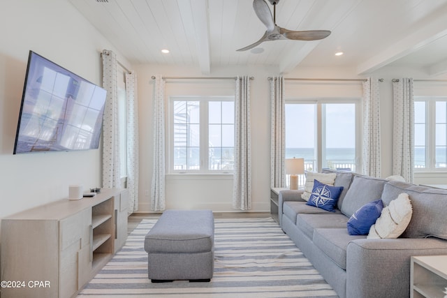 living room featuring beamed ceiling, wood-type flooring, ceiling fan, and a water view