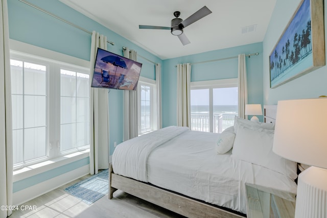 bedroom featuring a water view, ceiling fan, and access to exterior