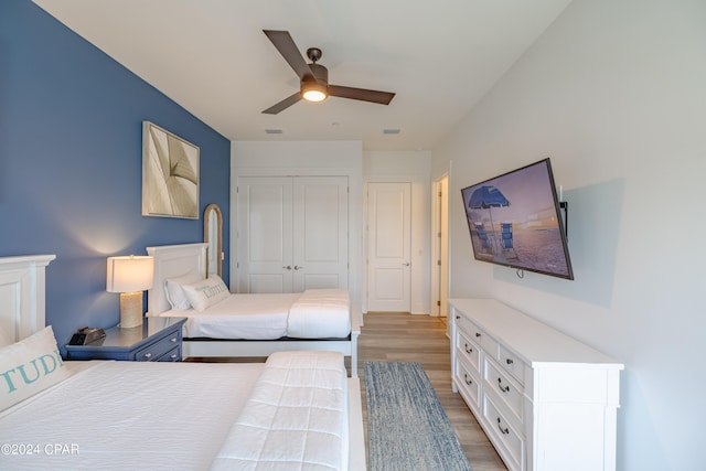 bedroom featuring wood-type flooring, ceiling fan, and a closet