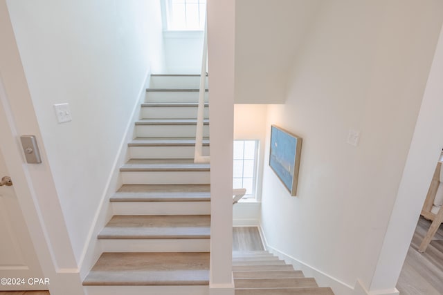 stairs featuring a wealth of natural light and hardwood / wood-style flooring