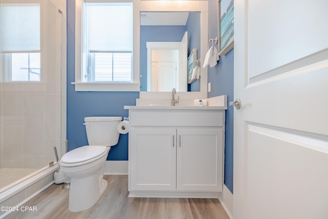 bathroom featuring tiled shower, plenty of natural light, hardwood / wood-style flooring, and toilet