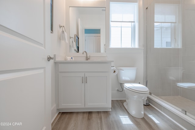 bathroom featuring hardwood / wood-style floors, vanity, toilet, and a tile shower