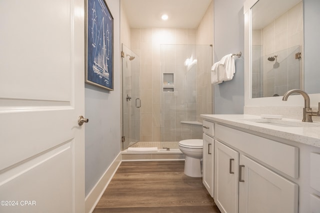 bathroom featuring hardwood / wood-style floors, a shower with shower door, toilet, and large vanity